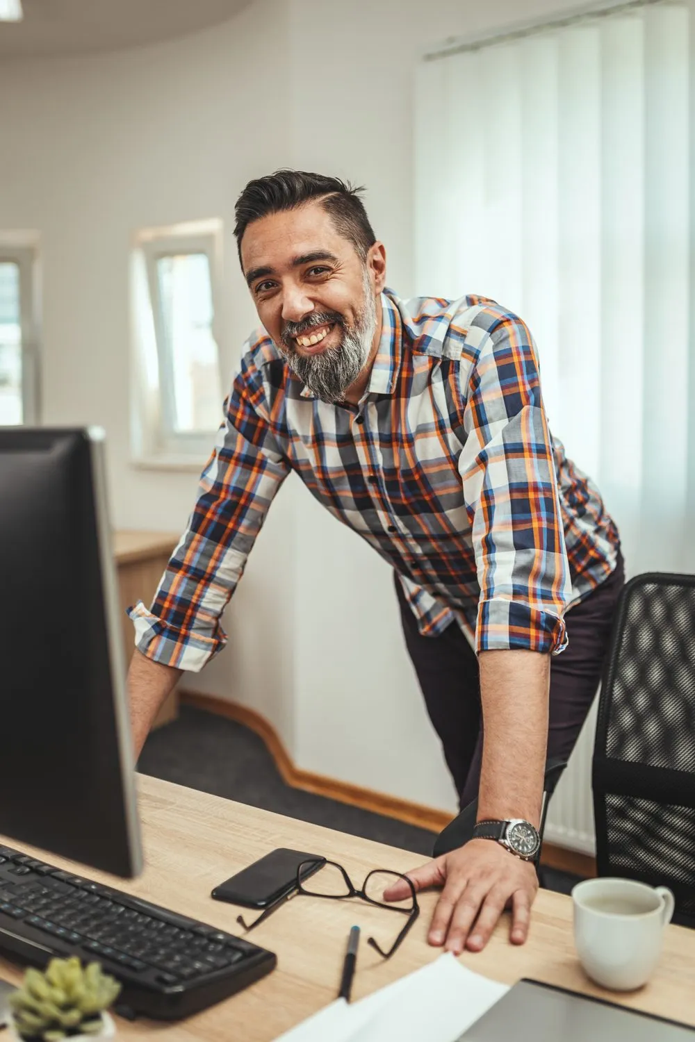 A smiling man at his desk in a modern office